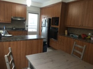 Cuisine moderne dans une maison de chambre avec armoires en bois finition élégante et appareils électroménagers en acier inoxydable ambiance chaleureuse et invitante.