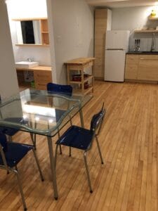 Appartement étudiant moderne avec cuisine équipée et salle à manger spacieuse montrant des meubles en bois clair et un sol en parquet idéal pour les étudiants.